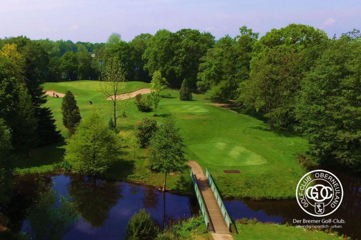 Blick über einen weitläufigen Golfplatz mit See