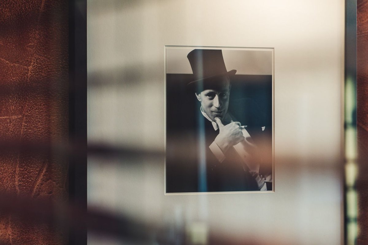 A framed picture of a man in a top hat on a white wall