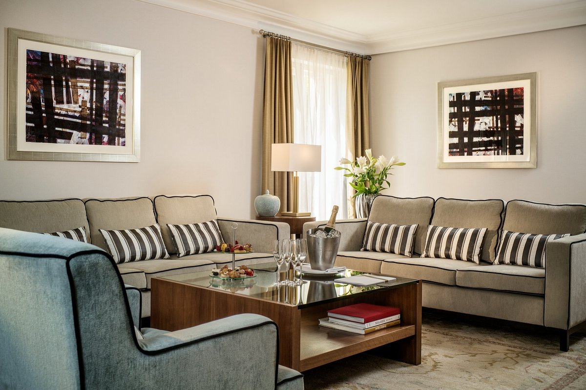 Einblick in den Wohnbereich mit blau goldenen Sofas und Sesseln einer Deluxe Suite des Hotels