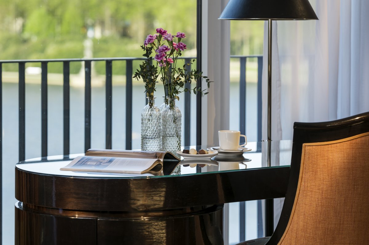 Desk with glass top, coffee and chocolates in the Superior Suite of the hotel in Bremen with a view of the lake in Bürgerpark