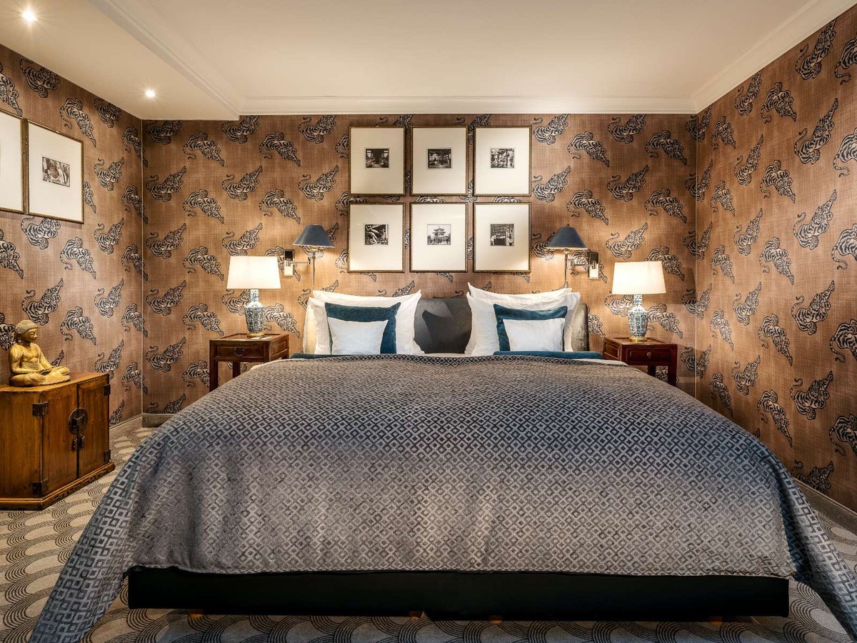 Front shot of a blue-grey covered bed in front of a patterned wall