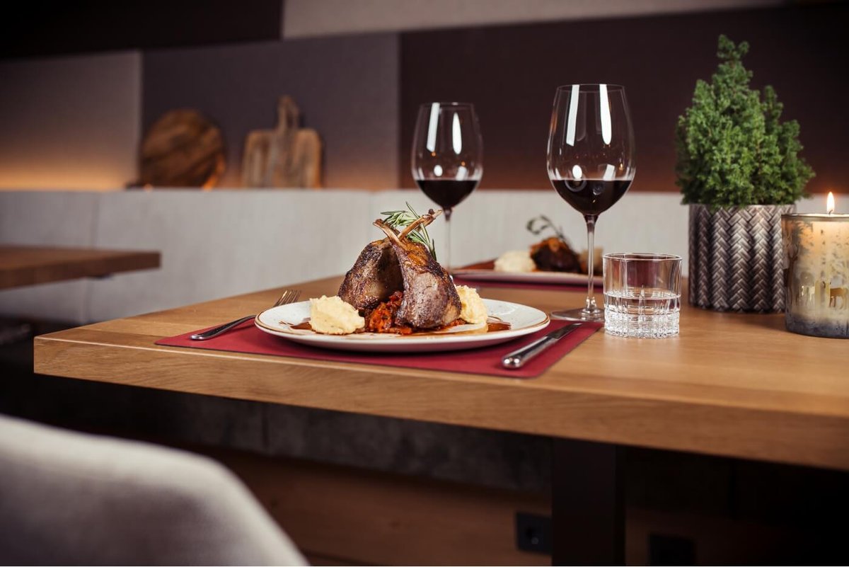 Eine leckere Fleischspeise und zwei Gläser Rotwein im Top-Restaurant Kitzbühel