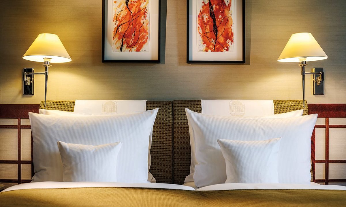 Gemachtes Doppelbett mit Bildern über dem Kopfteil in einem Zimmer des Luxushotels Bremen