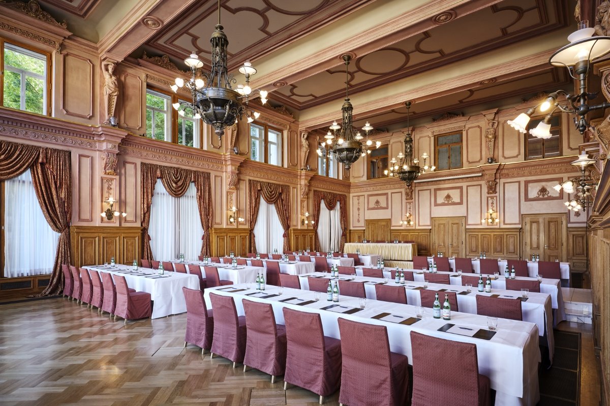 An impressive hall with set tables and beautiful walls in the event location in Baden Baden