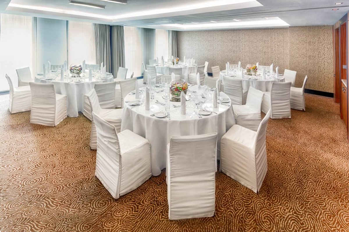 Aufnahme von einigen weiß gedeckten Tischen für eine Veranstaltung im Brocade Raum