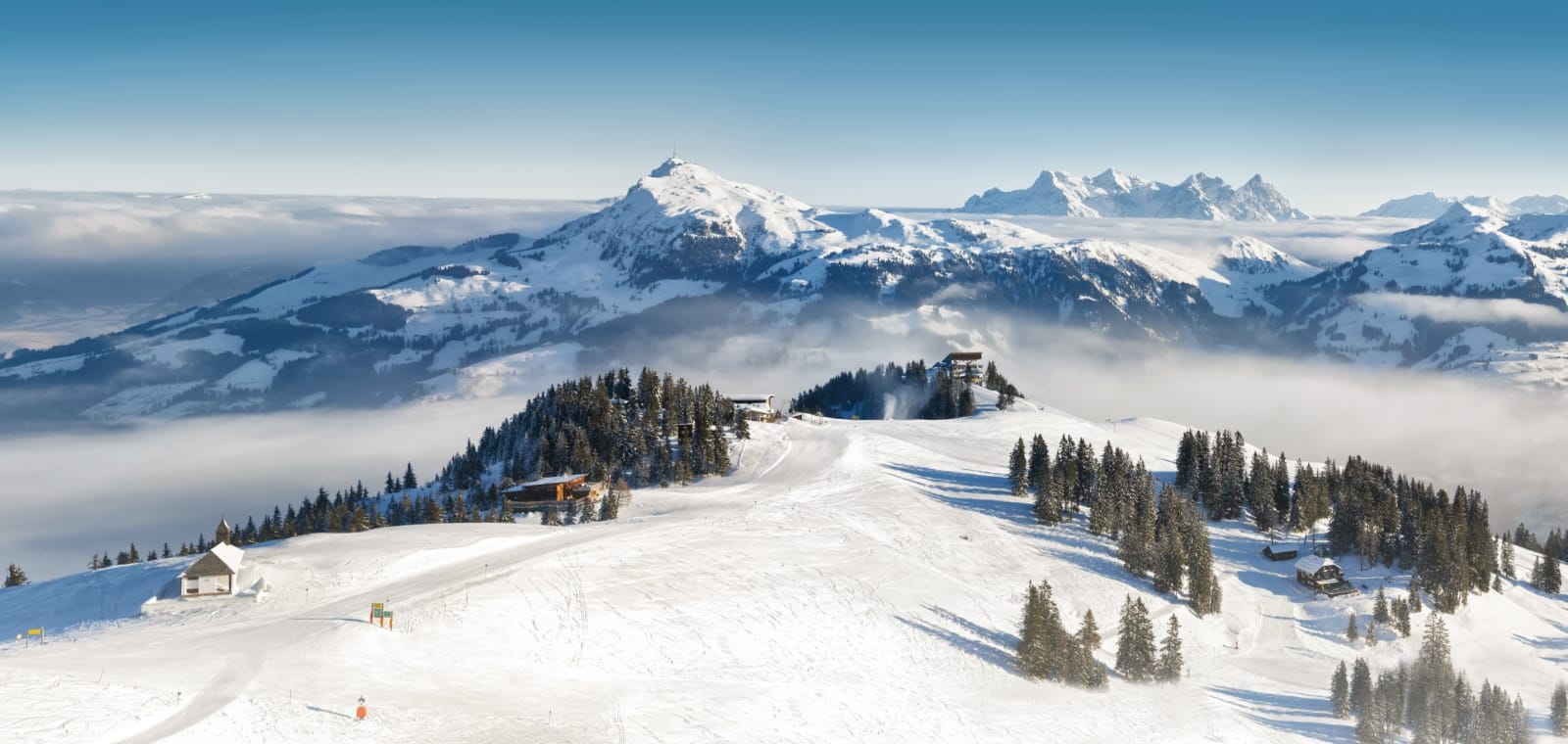 Picture of a snow-covered ski slope under a blue sky near the Kitzbühel ski resort