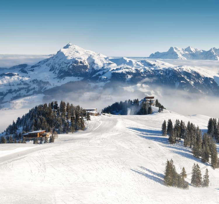 Verschneite Skipiste unter blauem Himmel in Tirol