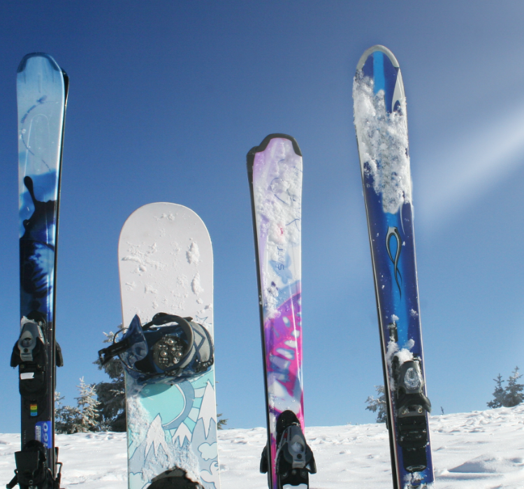 Skis and a snowboard in front of a sunny winter landscape in Austria