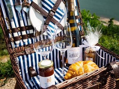 Close up of picnic basket with cutlery, plates, glasses, a bottle and some goodies