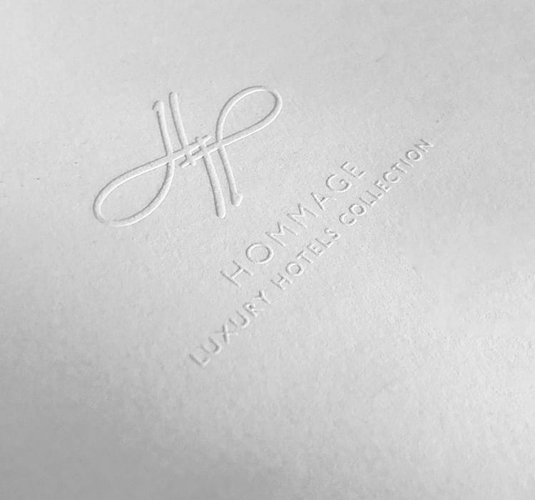 Das Logo der Hommage Hotels eingedruckt auf weißem Papier