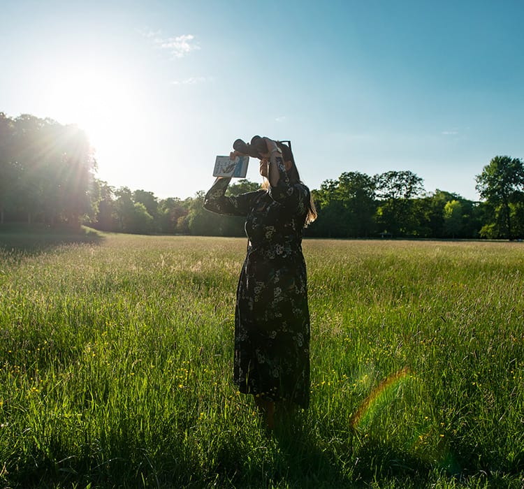 A woman watches birds in the sky with binoculars