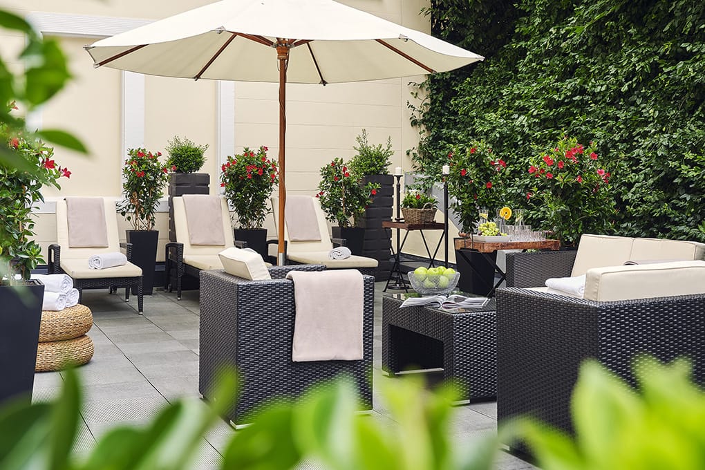 Gartenmobiliar mit Handtüchern, Pflanzen und Sonnenschirm auf der Terrasse des Royal Spa im Maison Messmer Wellnesshotel Baden Baden