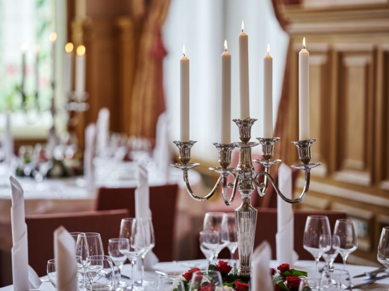Nahaufnahme eines Kerzenständers inmitten von roten Rosen in der Hochzeitslocation in Baden Baden