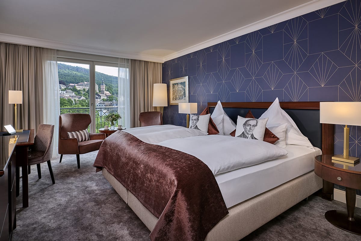 Komfort Zimmer im Luxushotel Maison Messmer mit Doppelbett, braunem Mobiliar und Blick auf Baden Baden