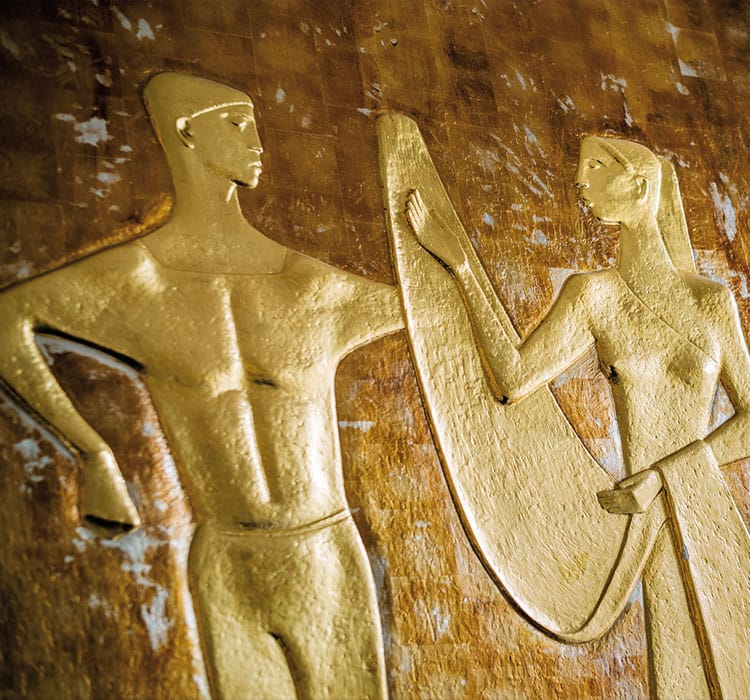 Detailaufnahme von vergoldeten ägyptischen Figuren an der Wand des Hommage Hotels