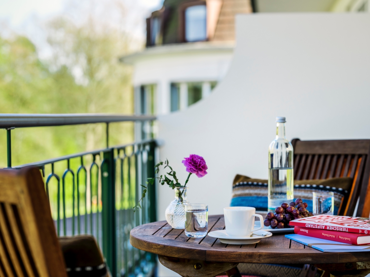 Holztisch, Kaffeetasse, Bücher und Trauben auf dem Balkon der Junior Suite im Luxushotel Bremen