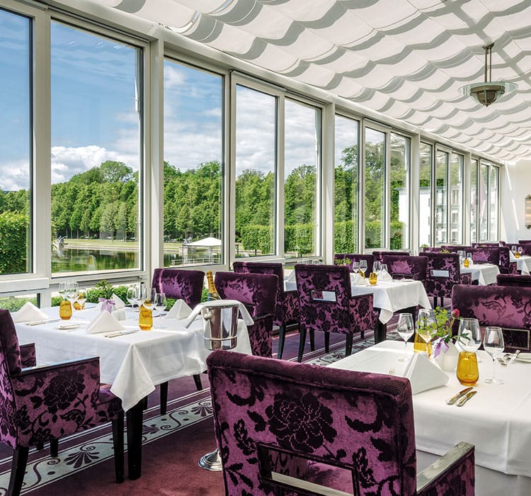 The spacious ballroom with purple chairs, set tables and panoramic view of the lake