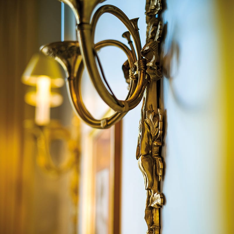 Detailaufnahme eines goldenen Kerzenleuchters an der Wand 