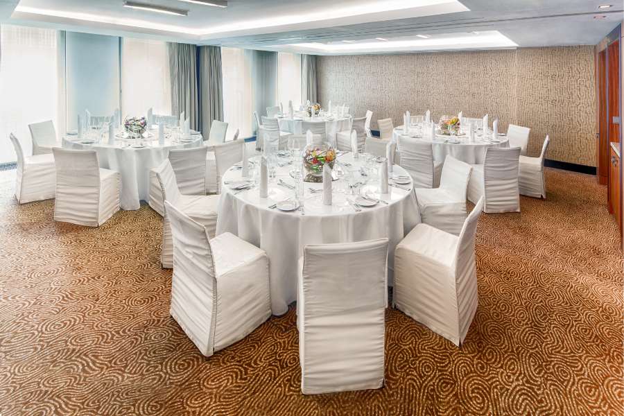 Einblick in den Brocade Veranstaltungsraum mit weißen Sitzmöglichkeiten und Tischen