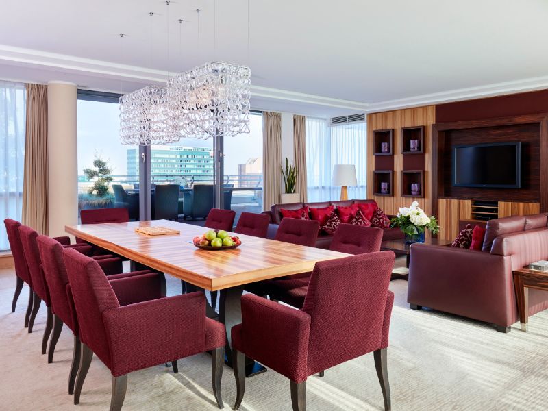 Cozy red chairs in the dining area of the Signature Suite, a hotel room in Dusseldorf