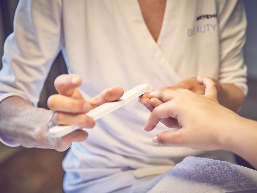 Nahaufnahme einer Kosmetikerin im Wellnesshotel Wiesbaden welche die Nägel einer Kundin feilt