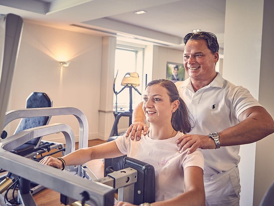 Ein Fitnesstrainer im Wellnesshotel Wiesbaden zeigt einer Kundin wie das Fitnessgerät funktioniert