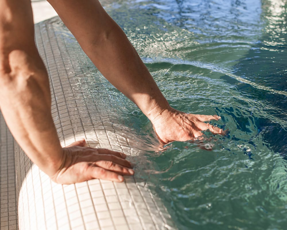 Someone reaches into the water of a swimming pool in the Beauty Therme of the Nassauer Hof, wellness hotel in Wiesbaden 