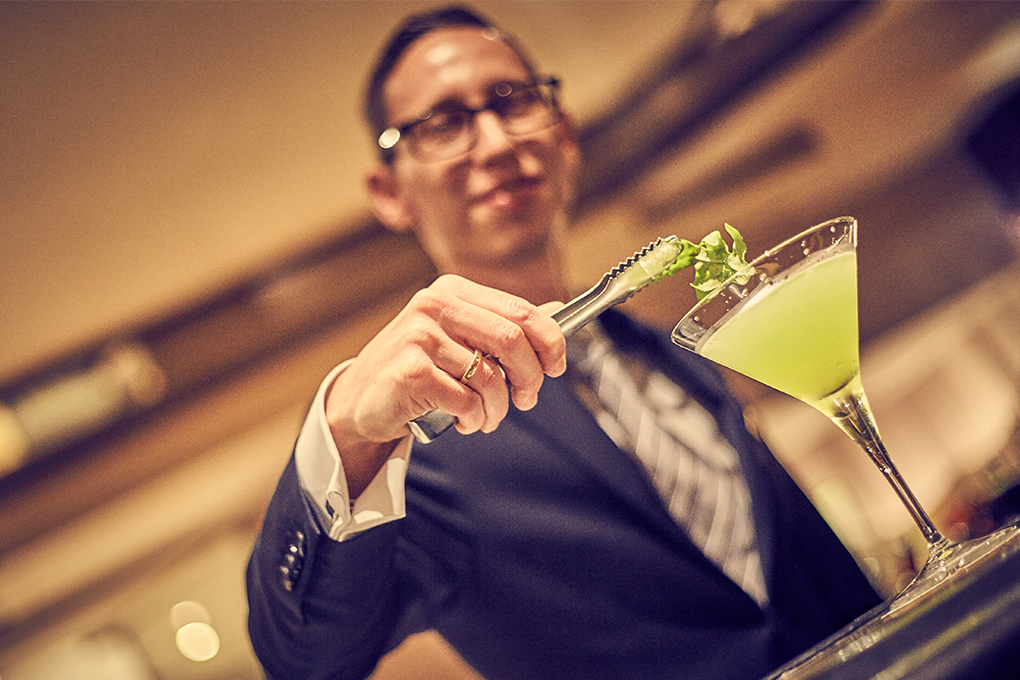 Aufnahme eines Barkeepers im Restaurant welcher gerade einen Cocktail verziert