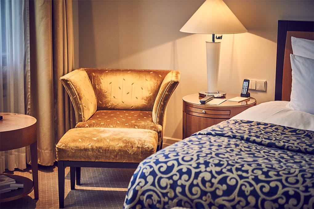 Aufnahme eines goldenen Sessels neben dem Bett in einem Superior Einzelzimmer des Hotels