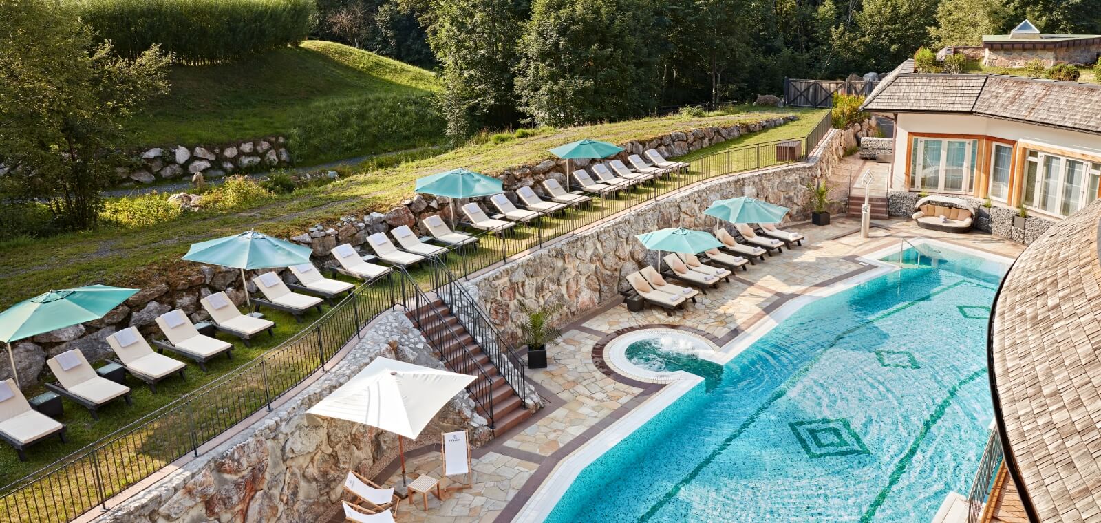 Der Pool und die Liegestühle im Außenbereich im Grand Alps Spa
